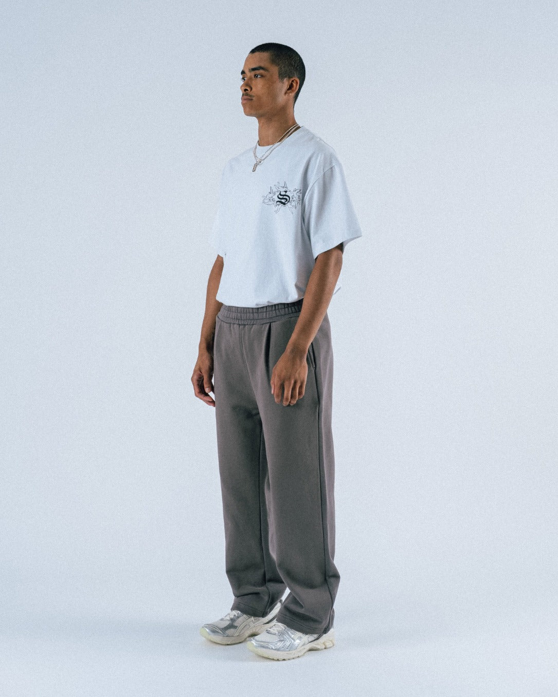 Person wearing a light gray t-shirt and dark gray pants on a white background