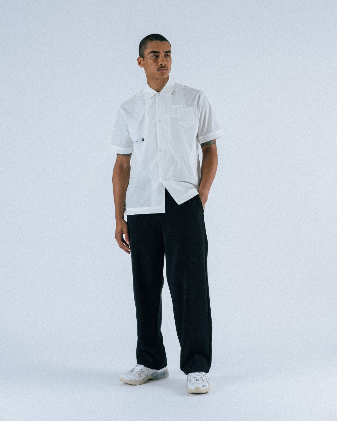 Person wearing a white shirt and black pants on a white background