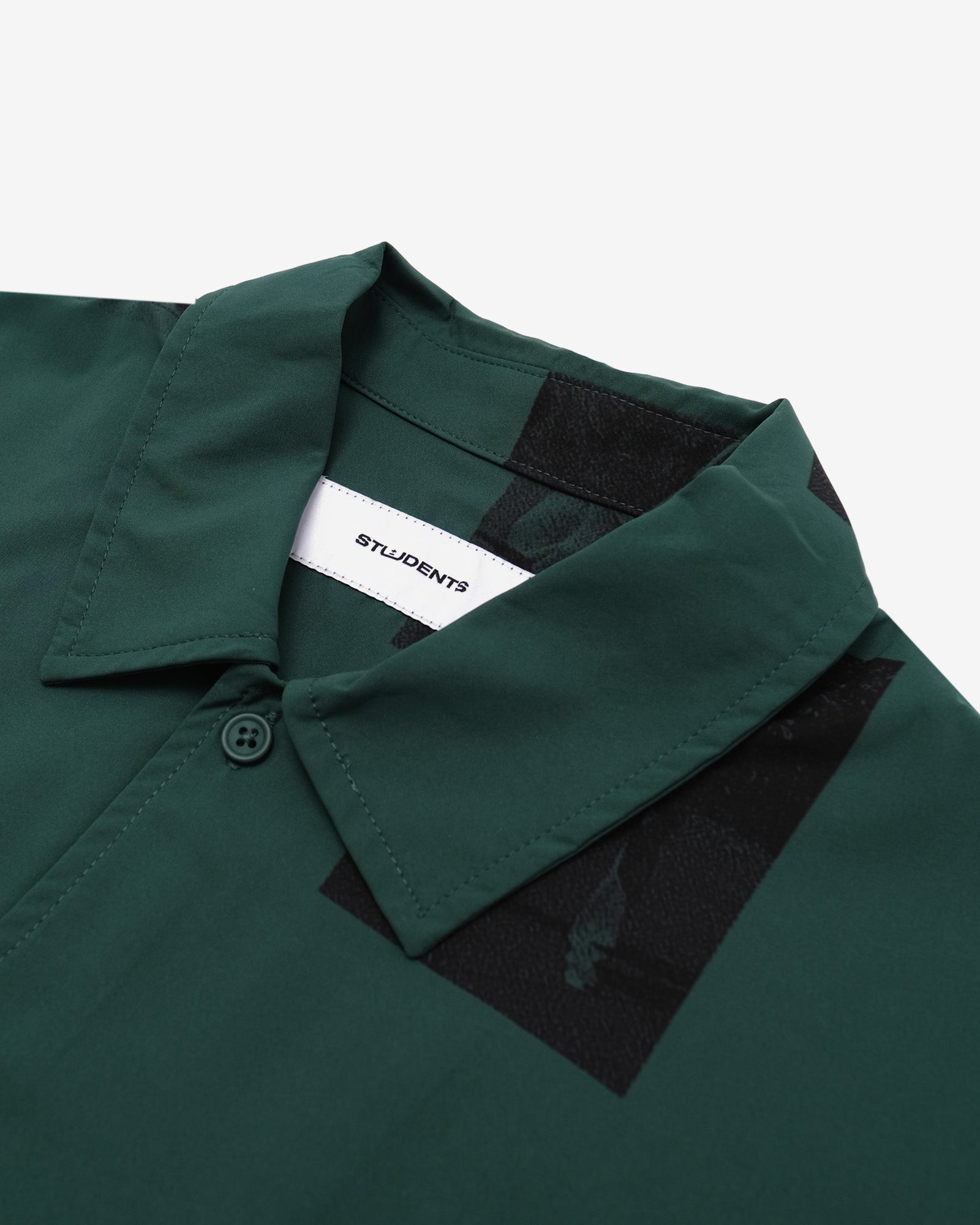 Close-up of a green shirt collar with a visible brand label on a white background