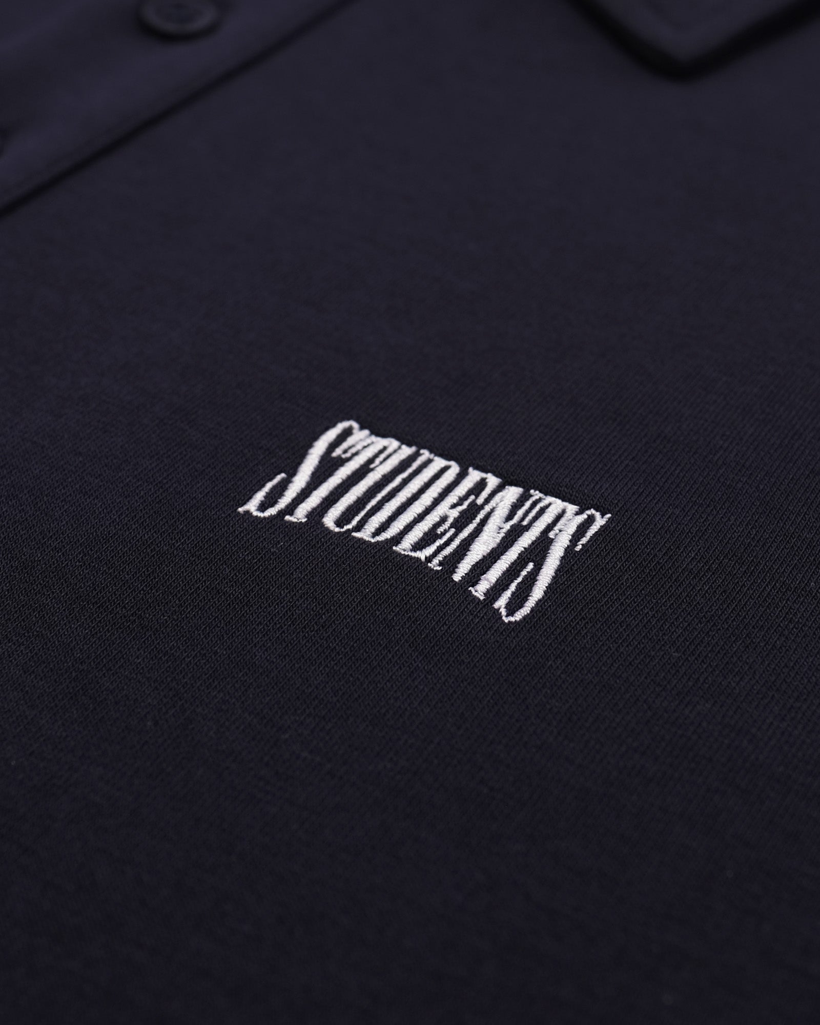 Black polo shirt with white 'STUDENTS' text embroidery on a dark background