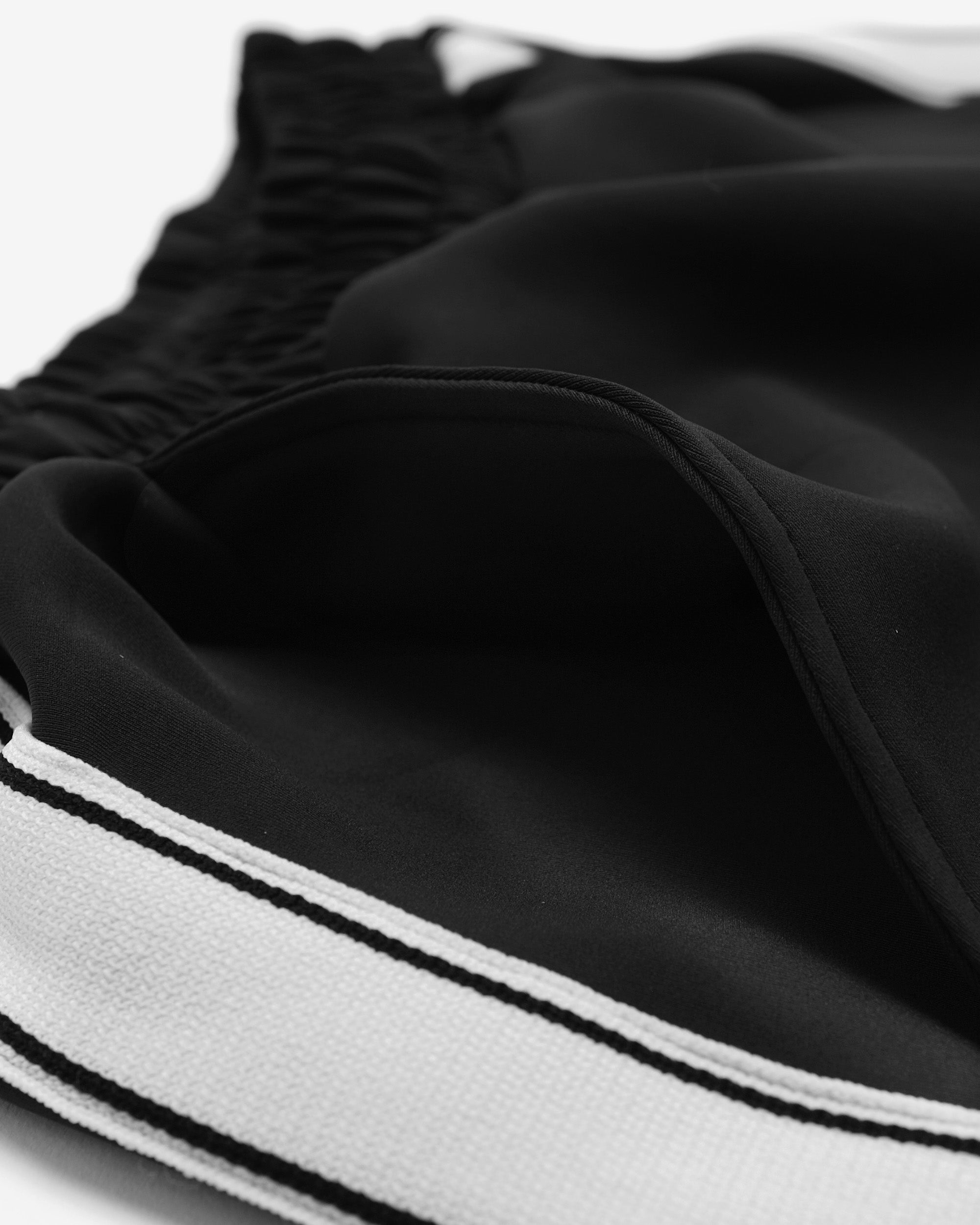 Close-up of a black garment with white trim on a white background