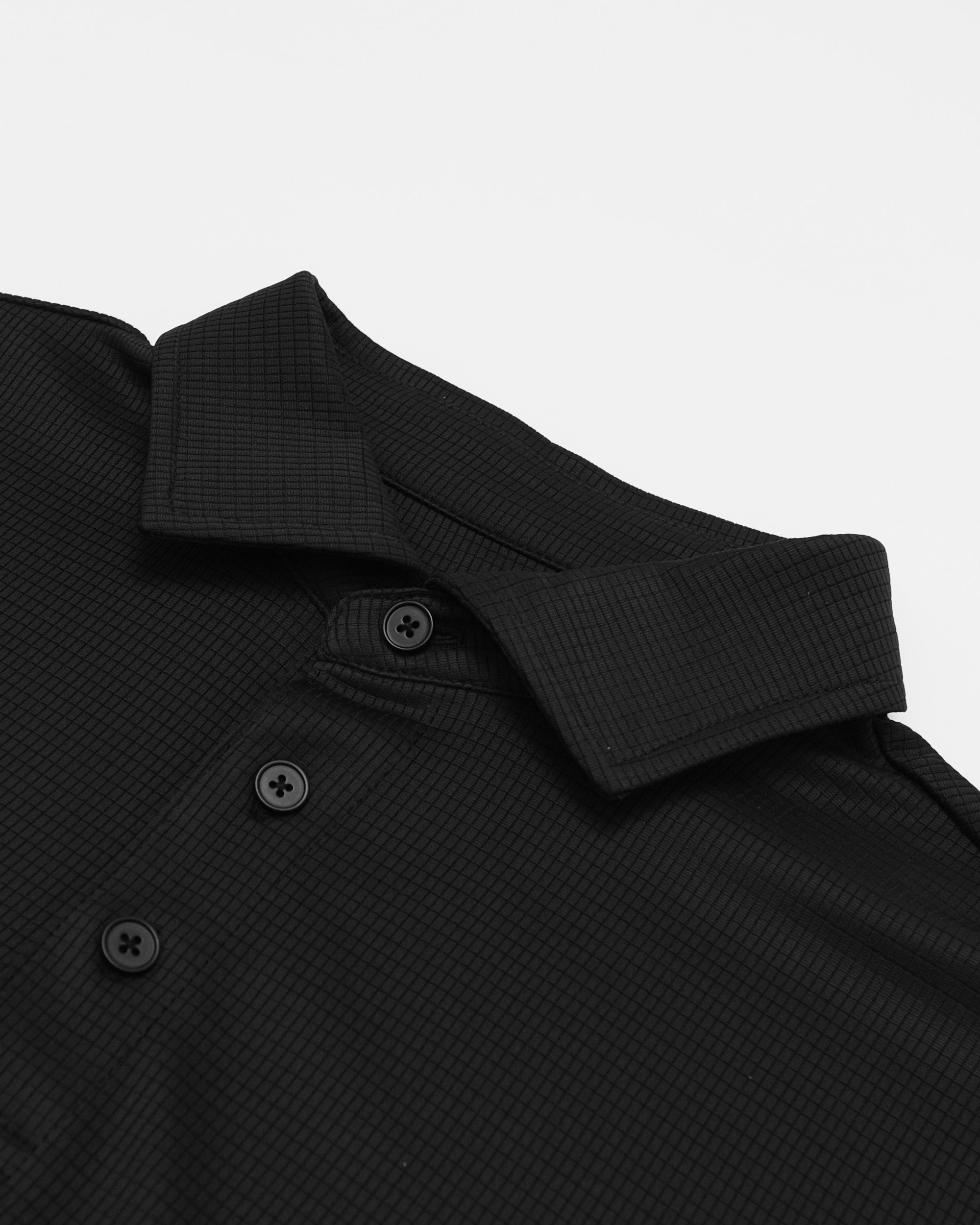 Close-up of a black textured shirt collar with buttons on a light gray background