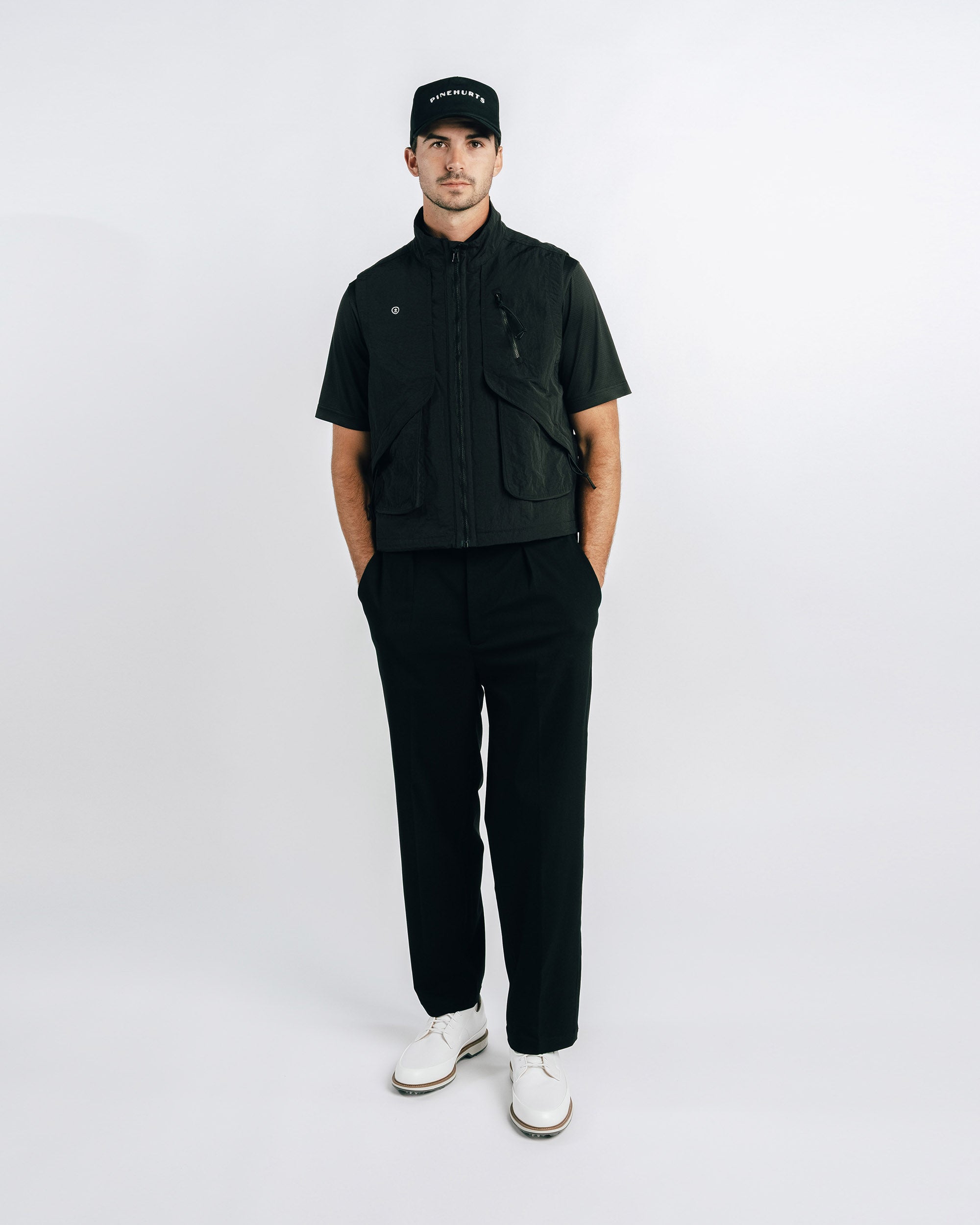 Man wearing a black outfit with a cap on a white background