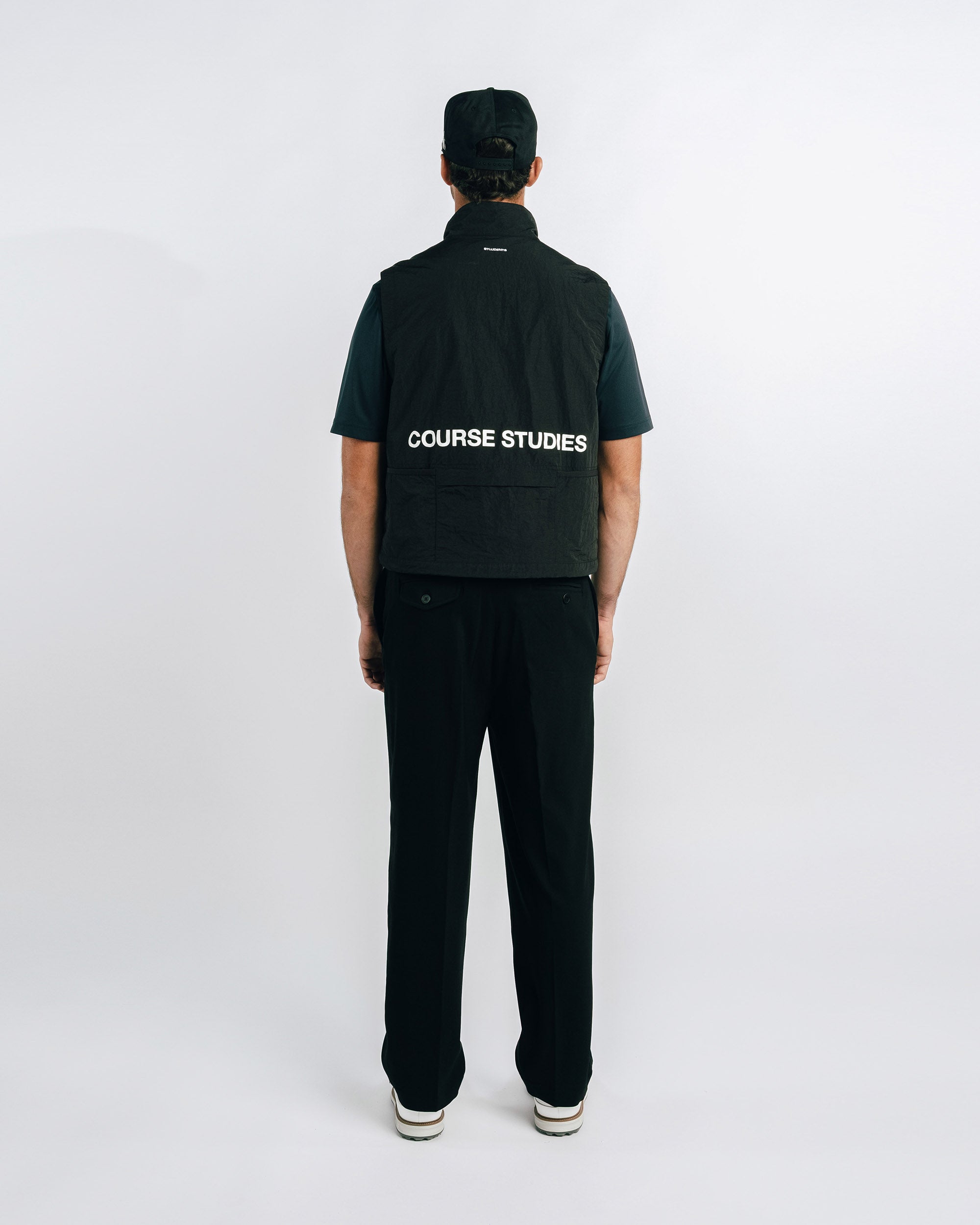 Person wearing a black jacket with 'Course Studies' branding on the back against a white background