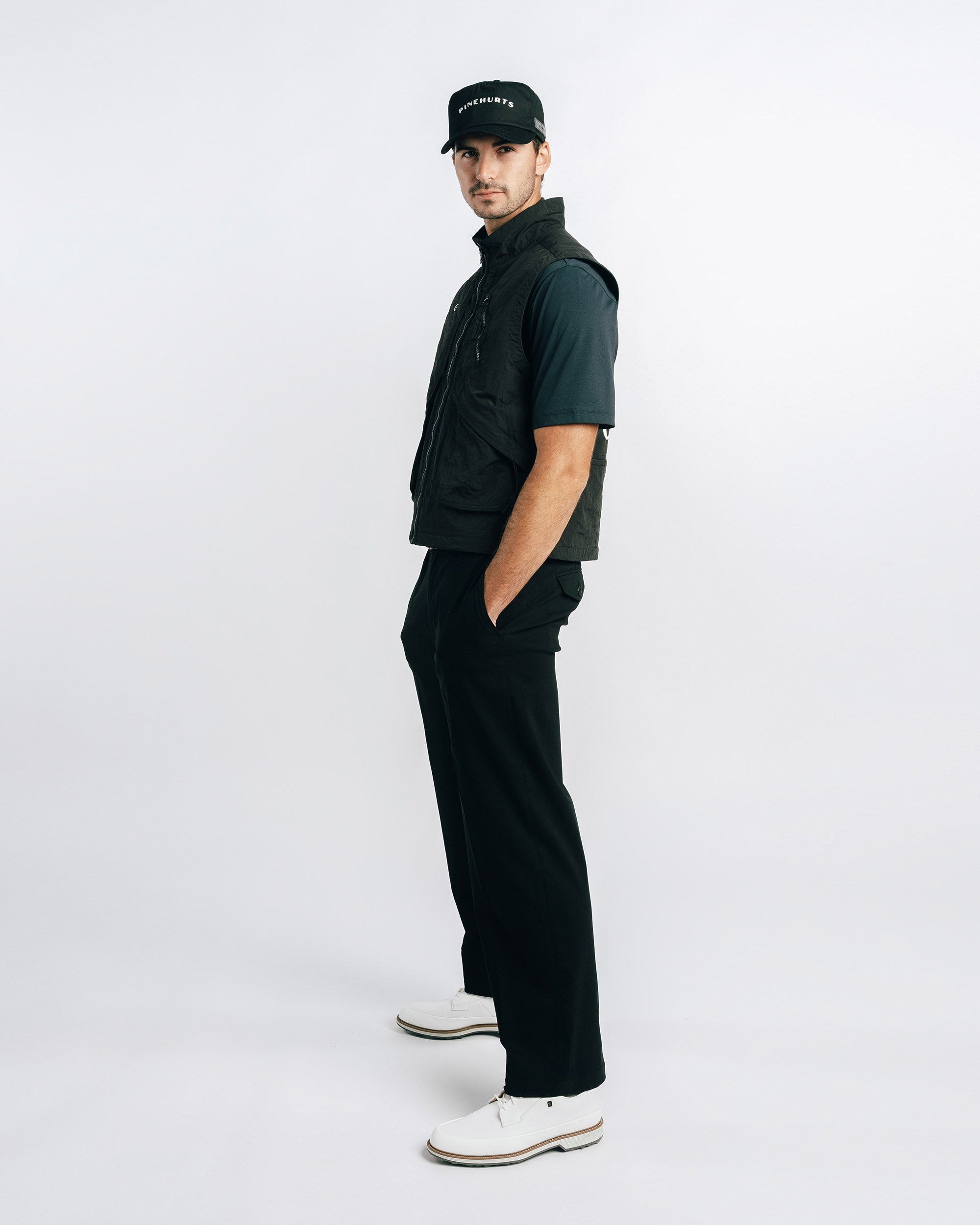 Man wearing a black outfit with a cap on a white background