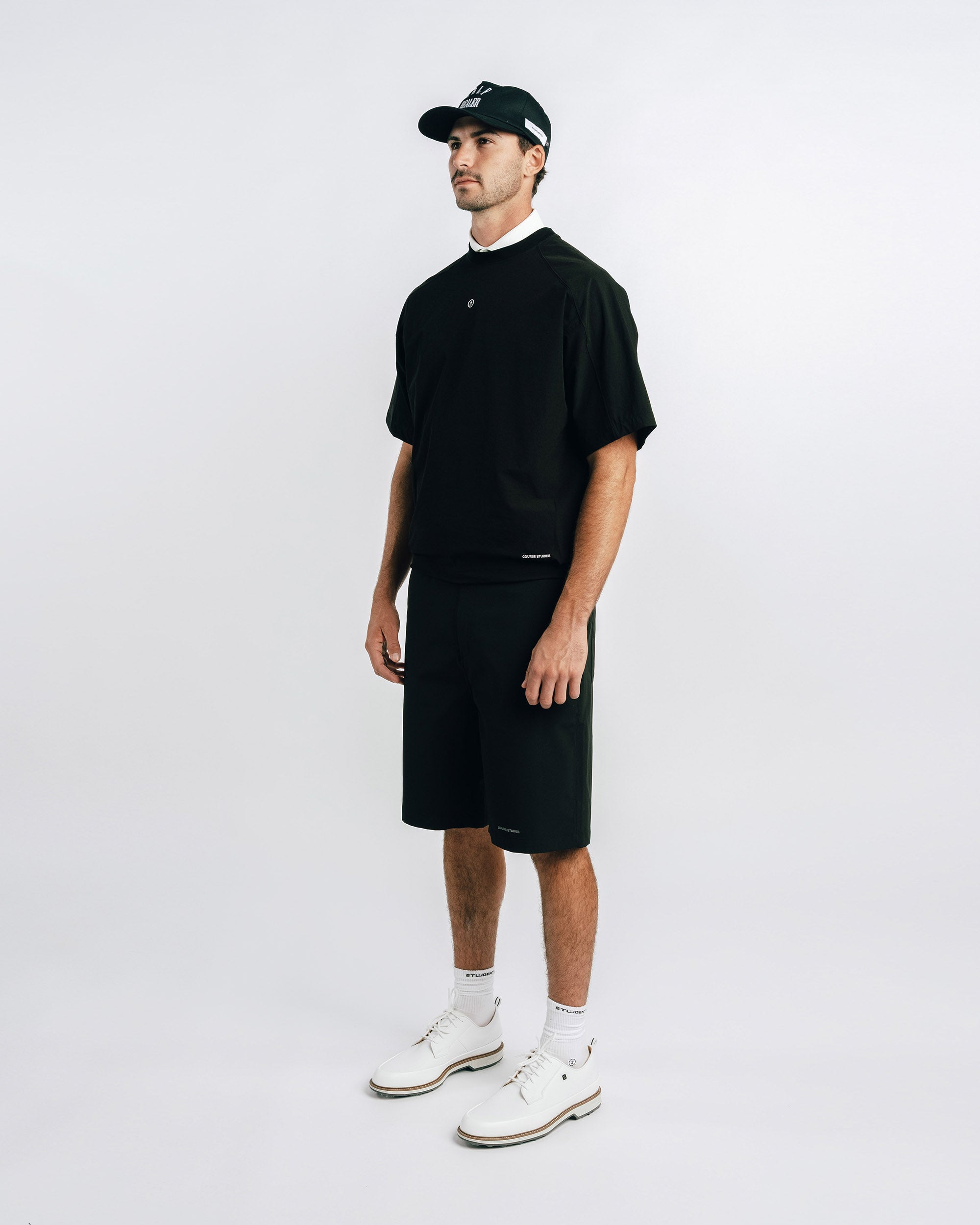 Man wearing a black outfit with a cap on a white background
