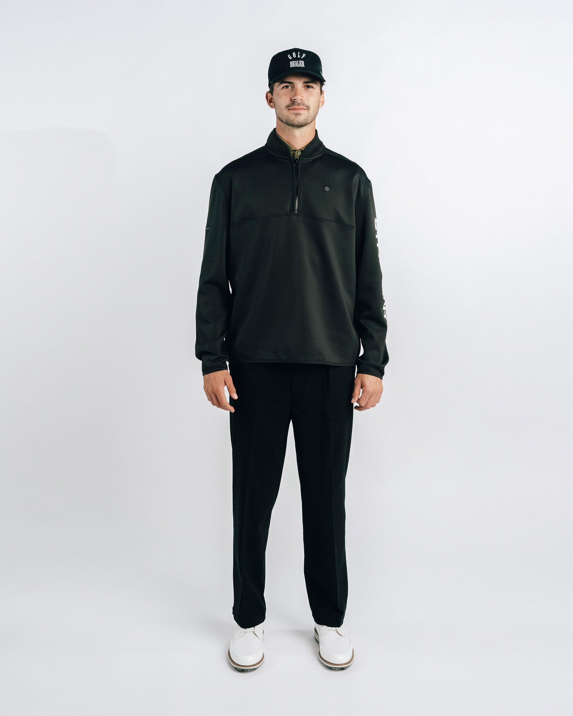 Man wearing a black jacket, black pants, and a black cap on a white background