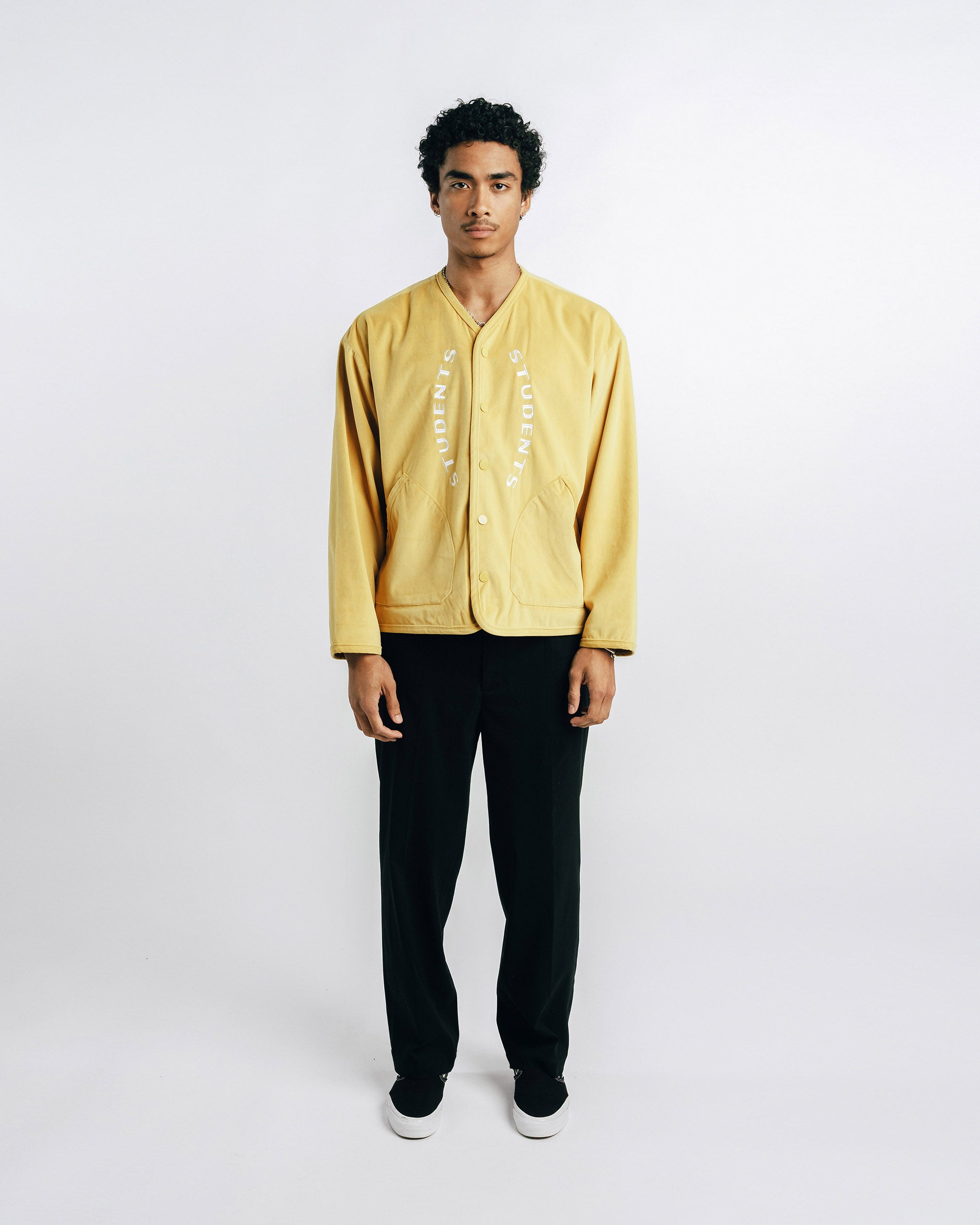 Man wearing a yellow jacket and black pants on a white background