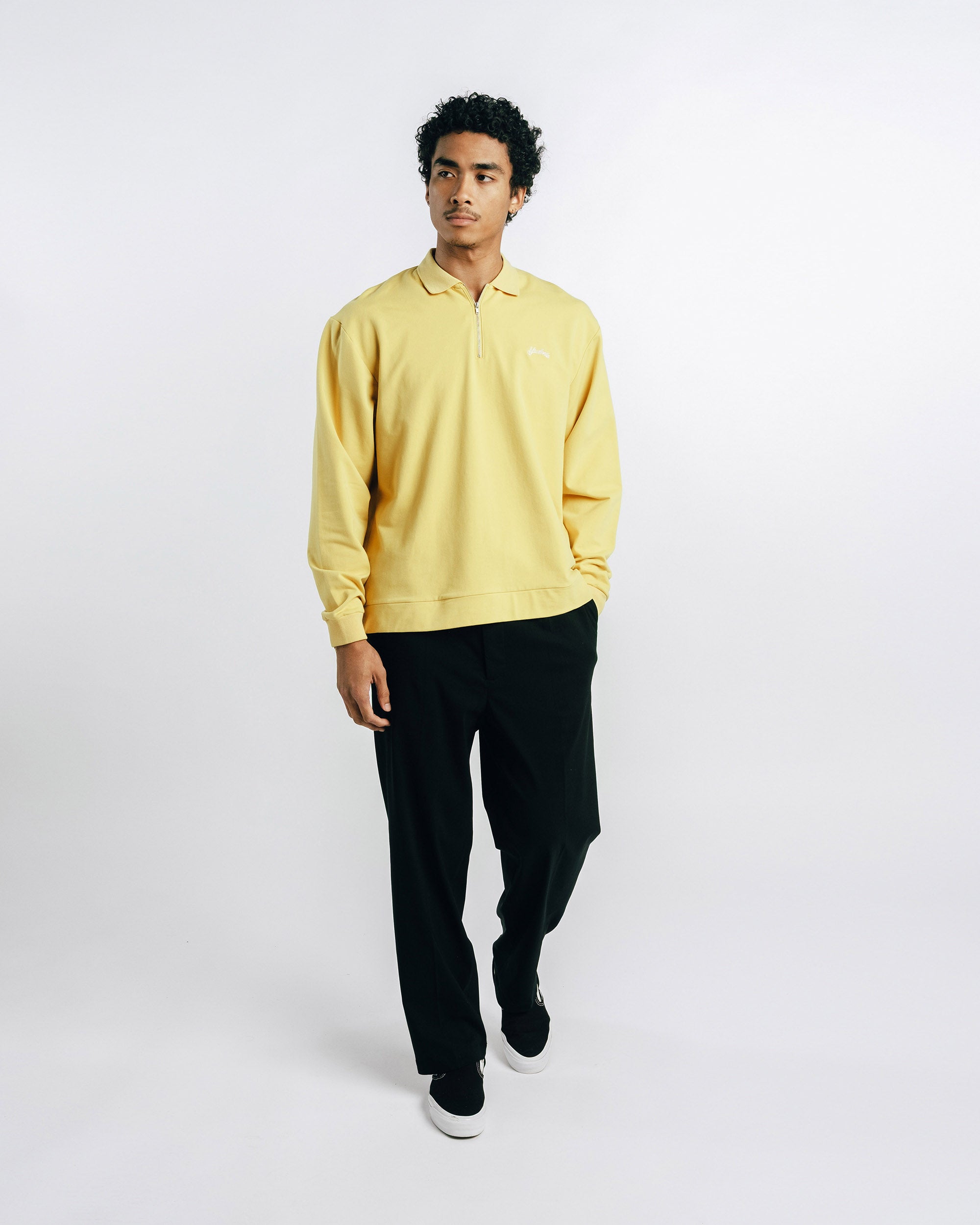 Person wearing a yellow shirt and black pants on a white background