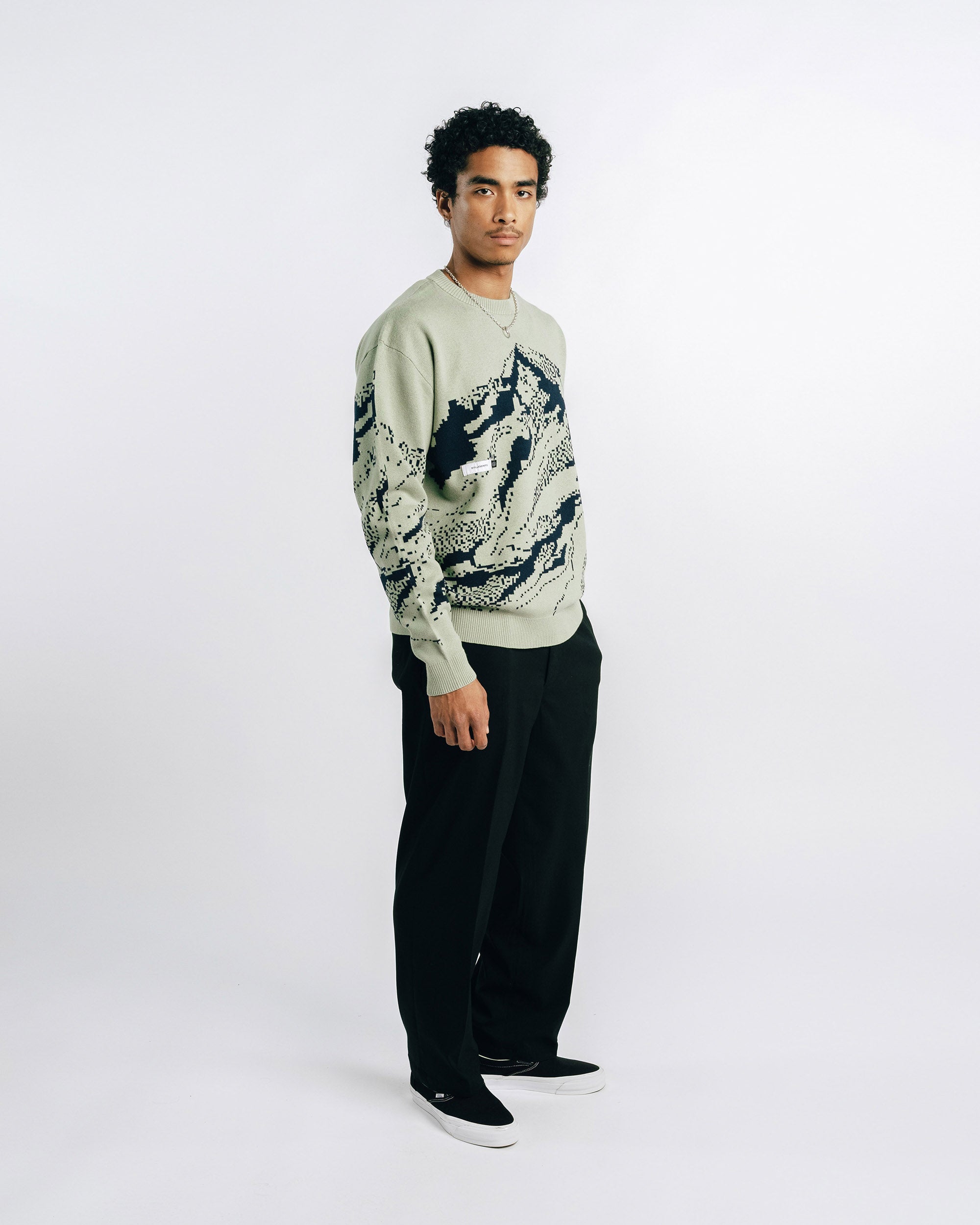 Green sweater with black mountain design on a white background