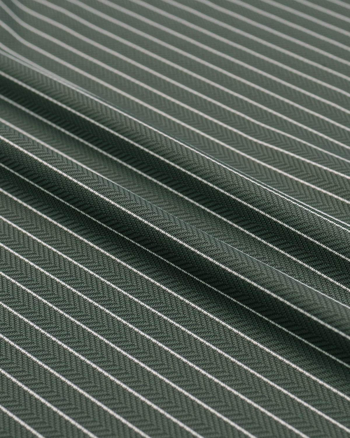 A close-up of dark green fabric with a fine white pinstripe pattern and a subtle herringbone weave texture.