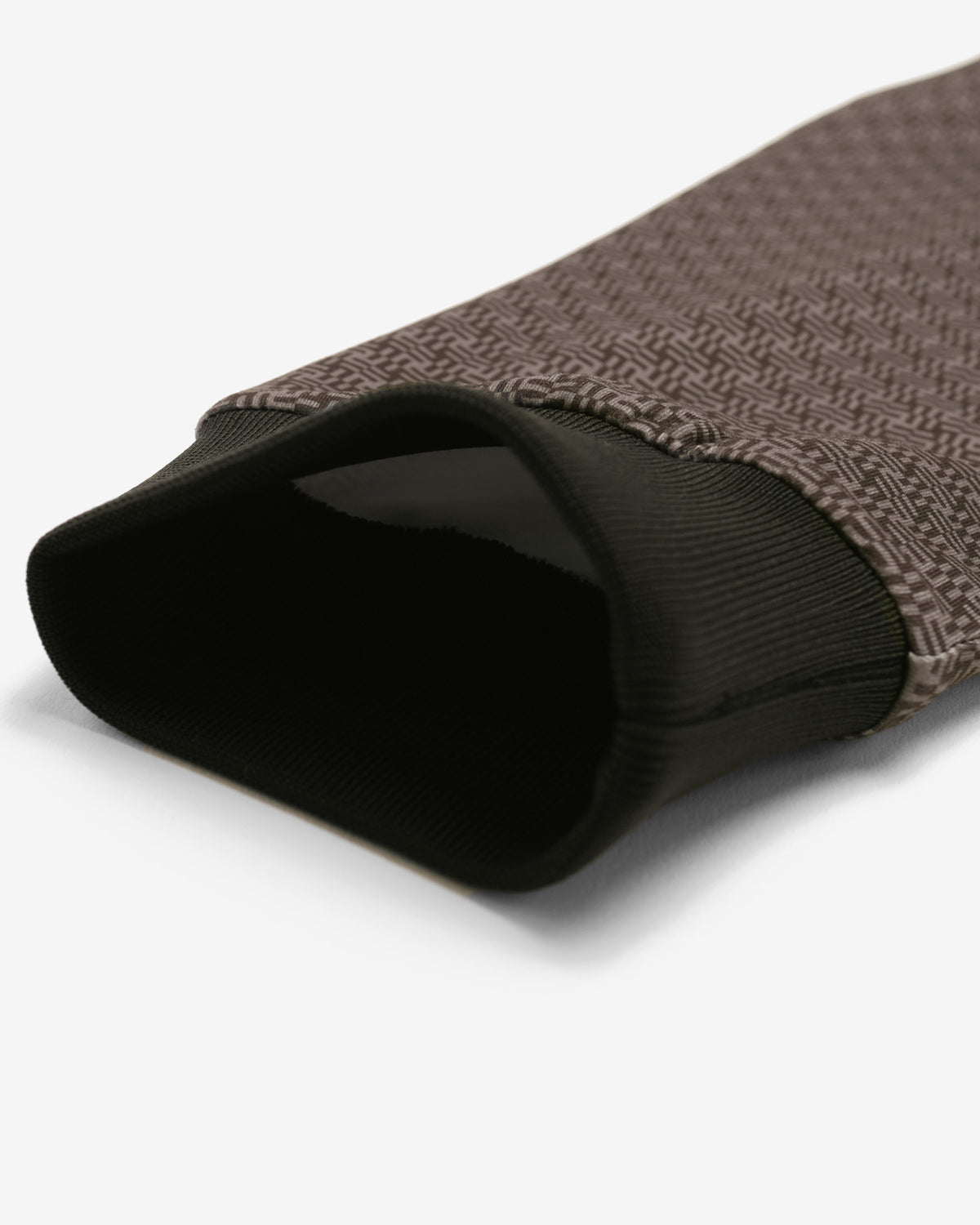 A close-up of a sleeve or sleeve cover featuring a brown and black herringbone pattern on the exterior and a solid black ribbed knit cuff on the interior, shown on a light gray background.