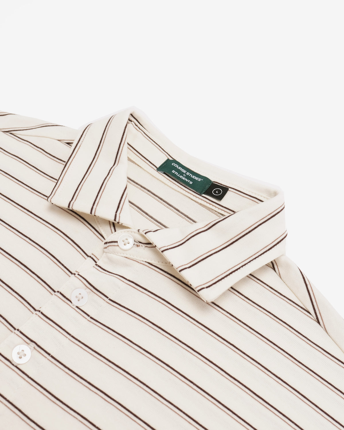 Close-up of a collared button-up shirt with thin vertical brown stripes on a warm off-white base, featuring a green neck label.