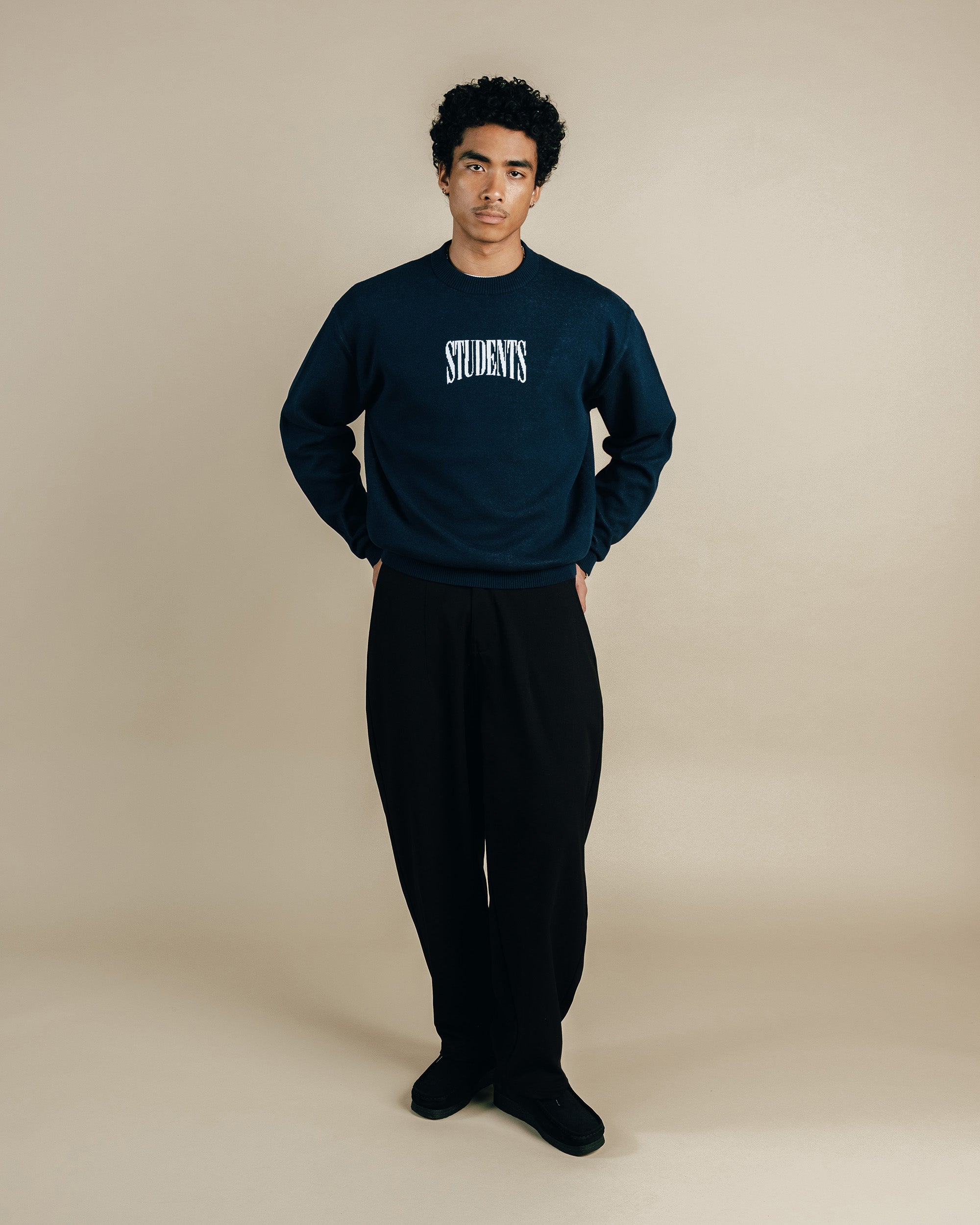 Person wearing a navy sweatshirt with 'STUDENTS' text on a beige background