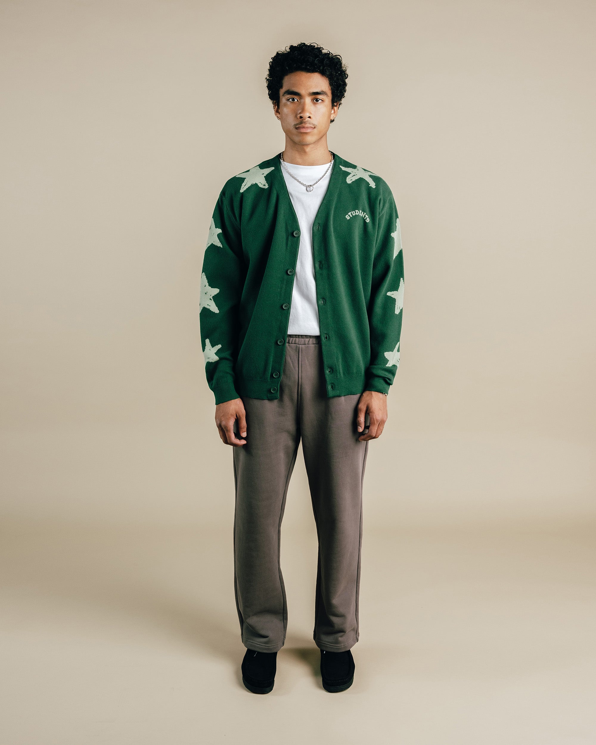 Person wearing a green cardigan with star patterns on a beige background