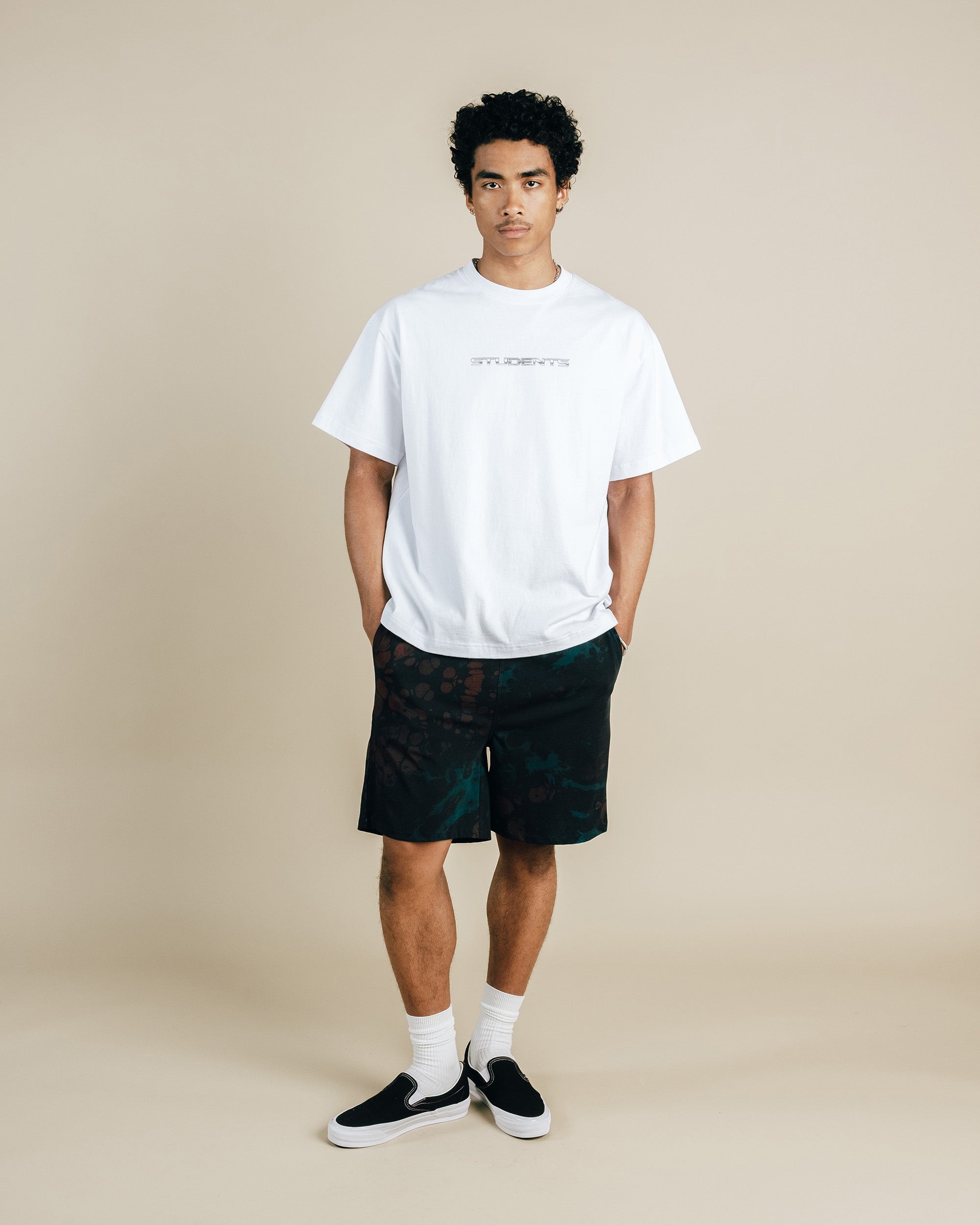 Man wearing a white t-shirt and black shorts on a beige background