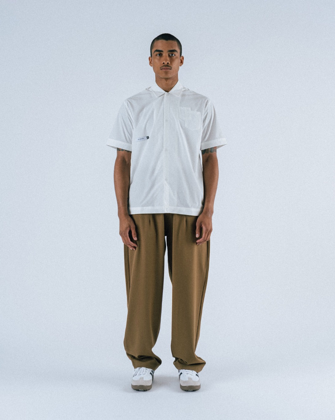 Person wearing a white shirt and brown pants on a white background