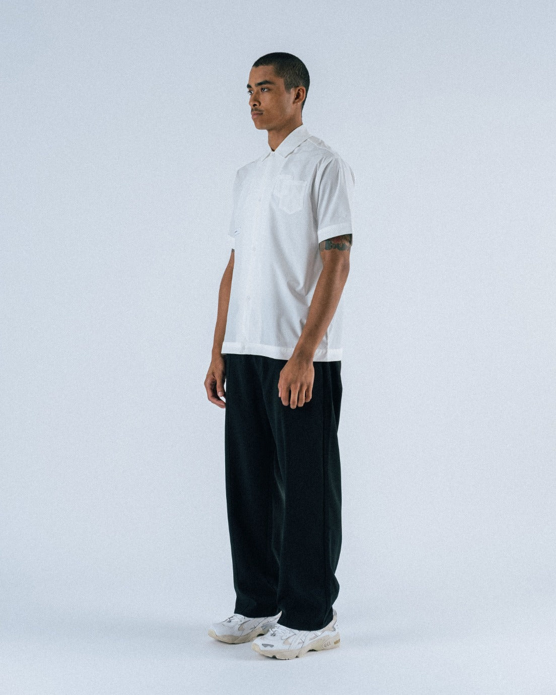 Person wearing a white t-shirt and black pants on a white background