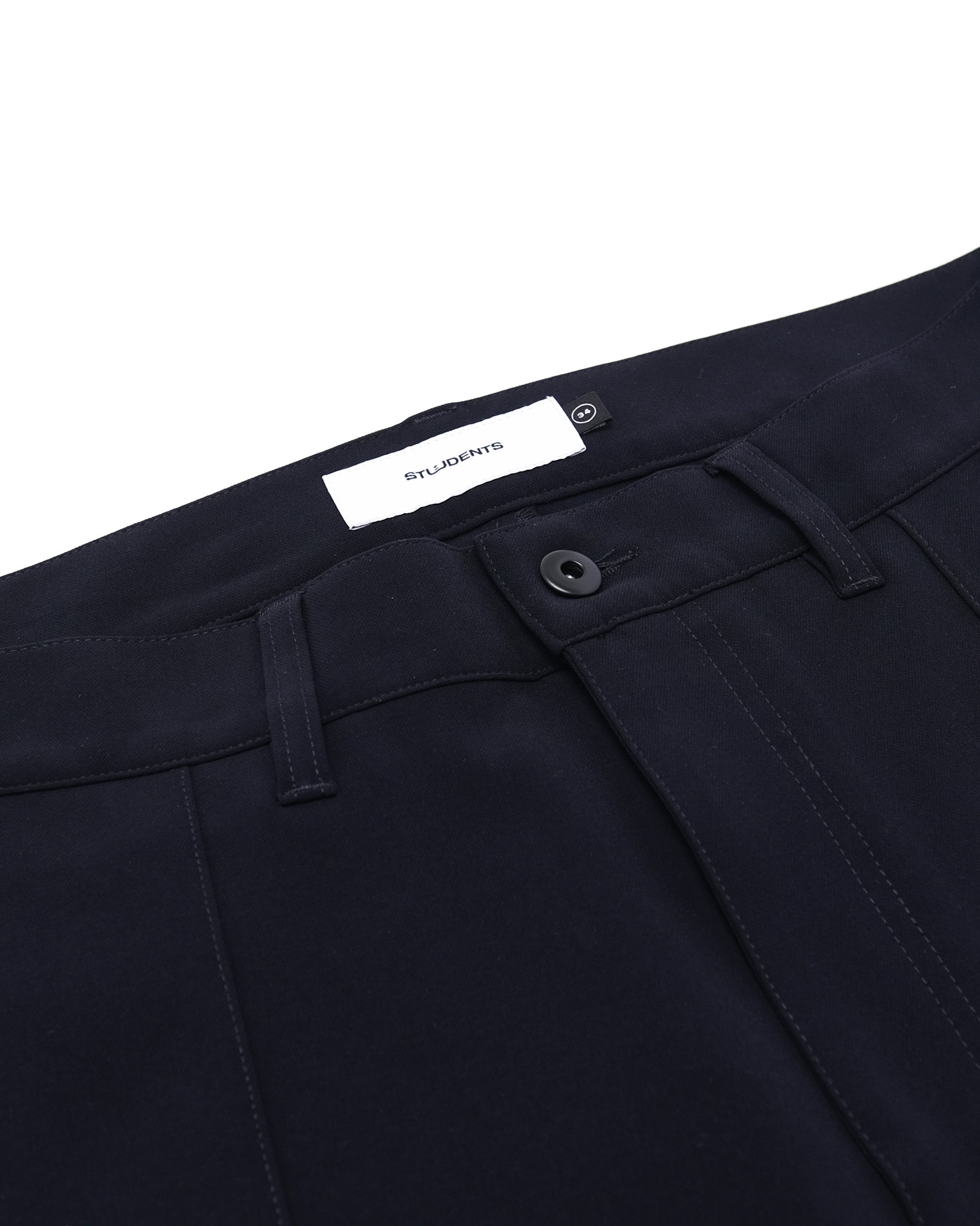 Close-up of dark blue pants with a brand label on a white background