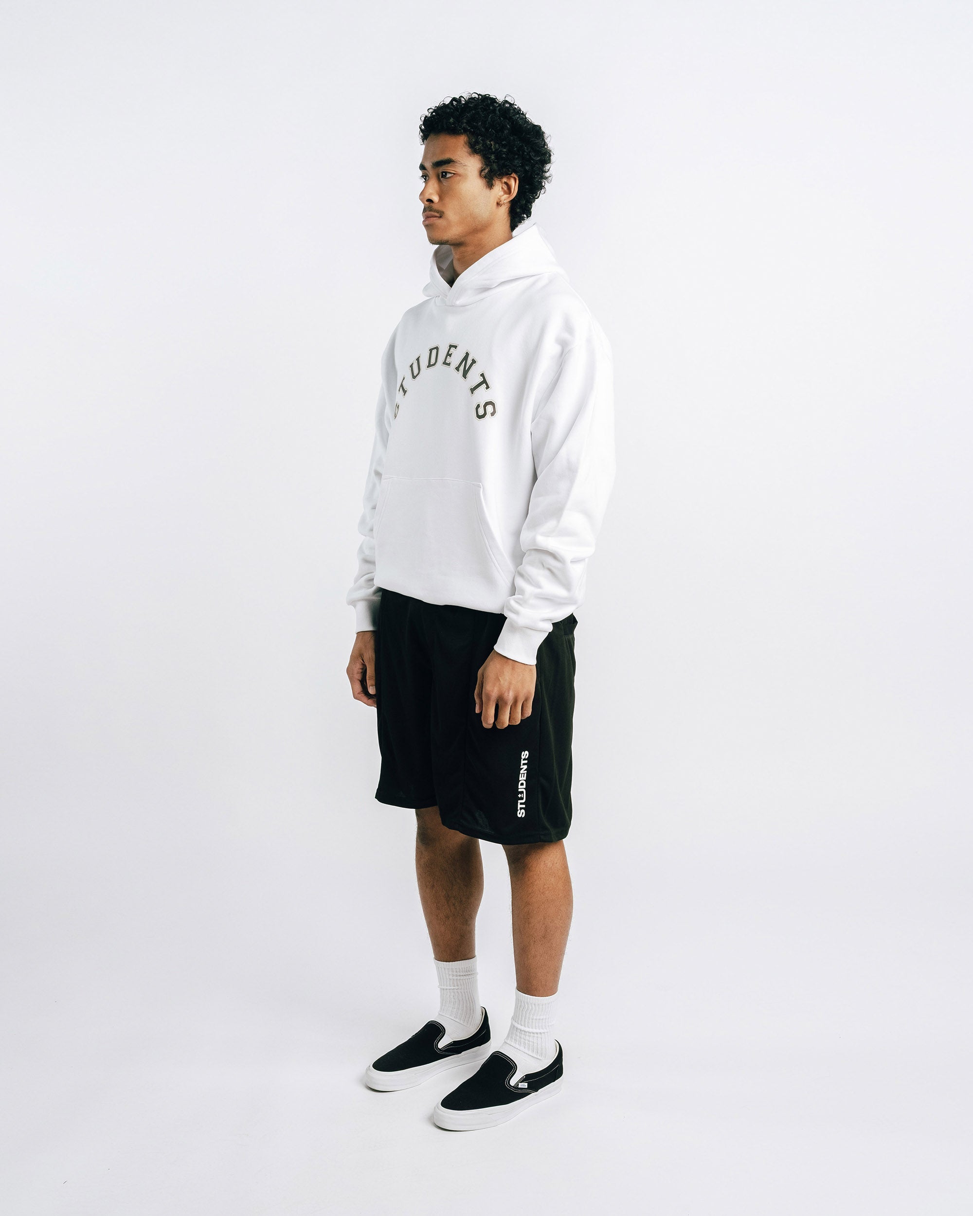 Person wearing a white hoodie with text and black shorts on a white background