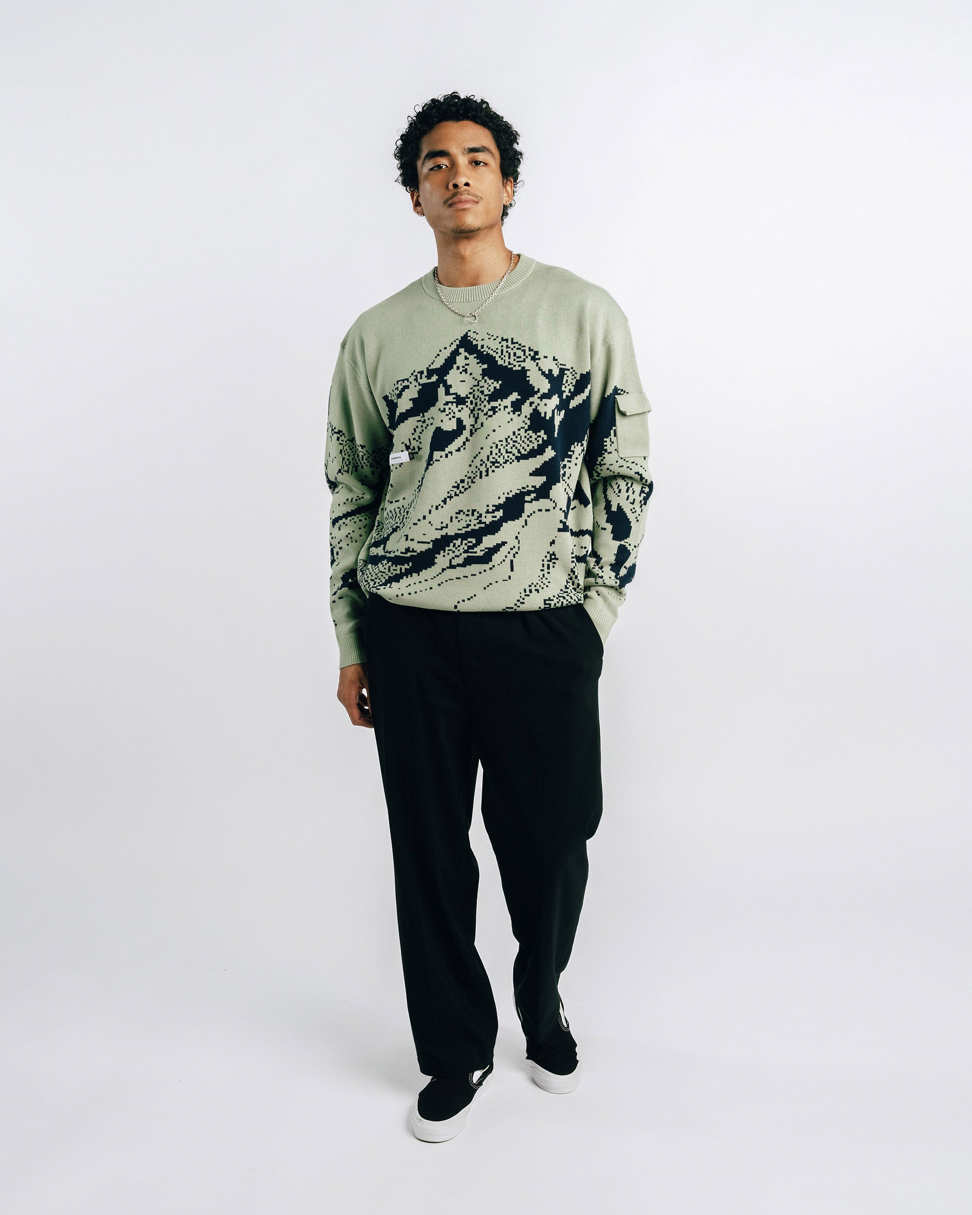 Green sweater with black mountain design on a white background