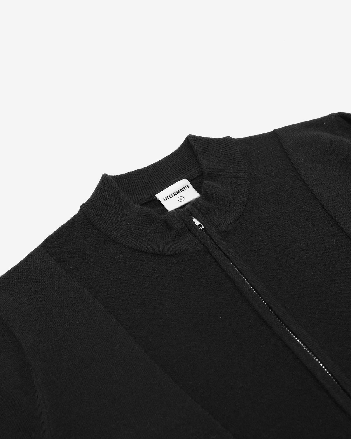 Close-up of a black ribbed knit zip-up sweater with a white brand label reading MURMillo, shown on a light gray background.
