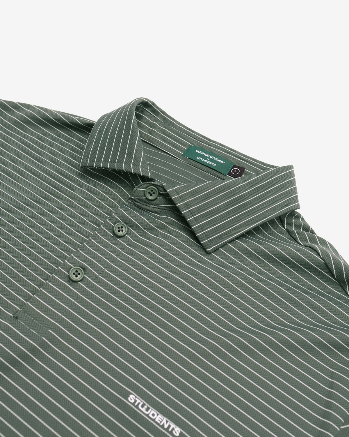 Close-up of a green polo shirt with thin white pinstripes, featuring a collar, button placket, and a white 'STUDENTS' logo printed on the chest.