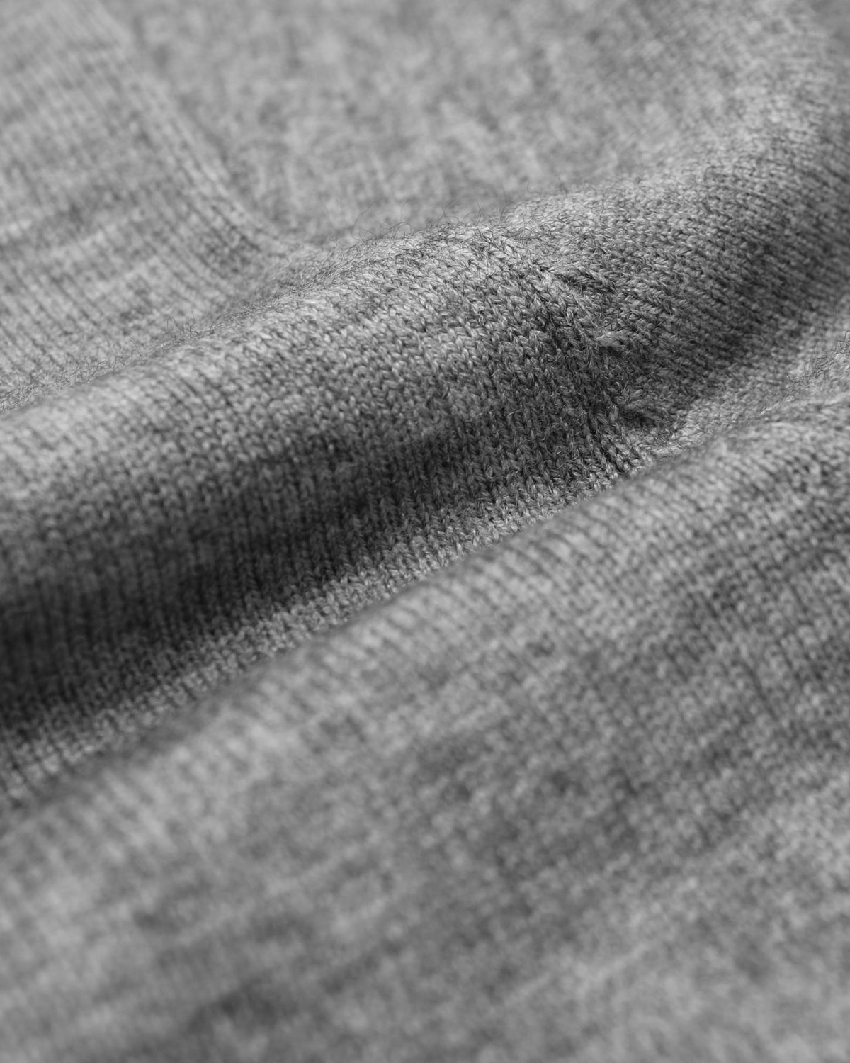 Close-up of a heather gray knit fabric texture with soft folds and ribbed stitching.