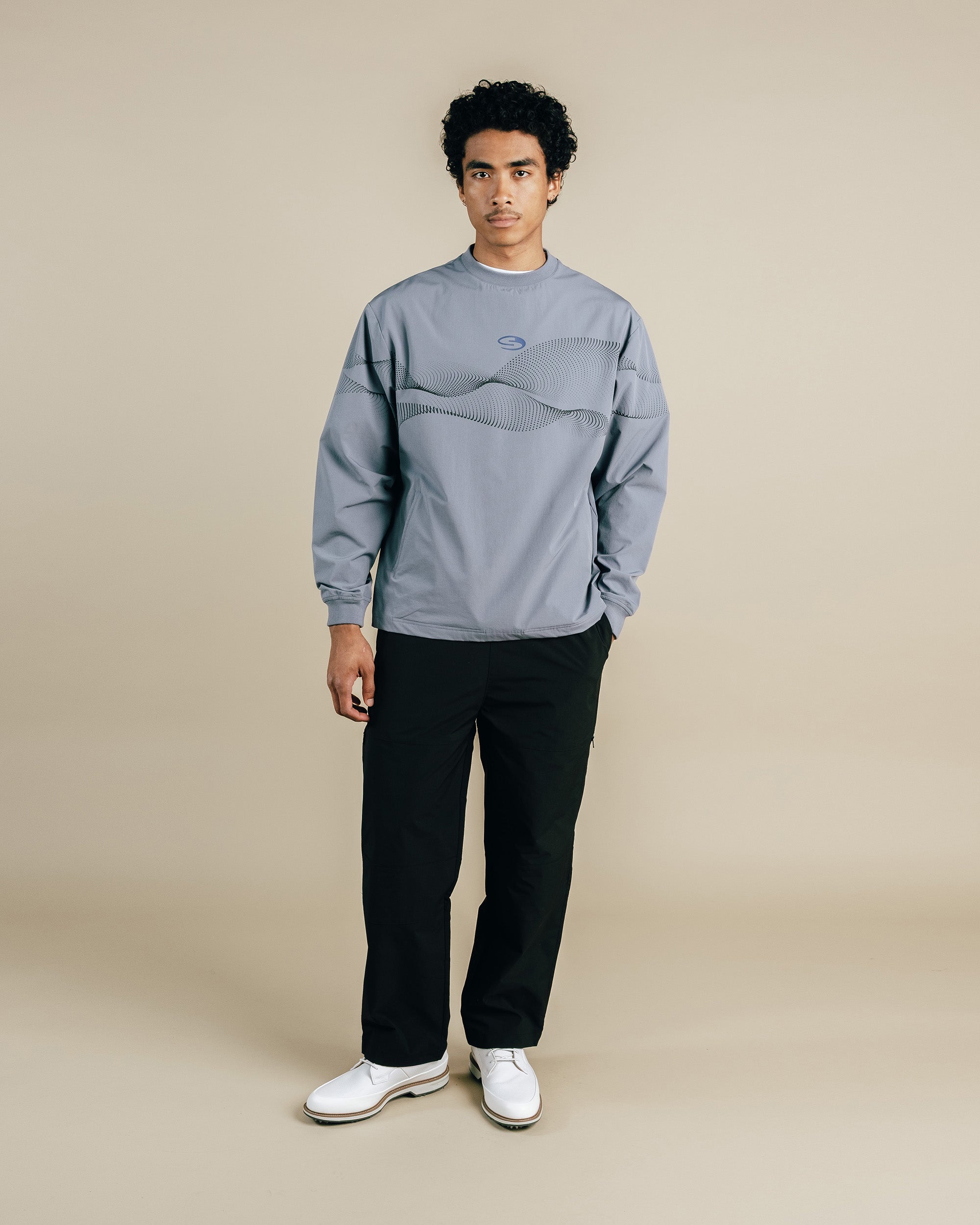Person wearing a gray sweatshirt and black pants on a beige background