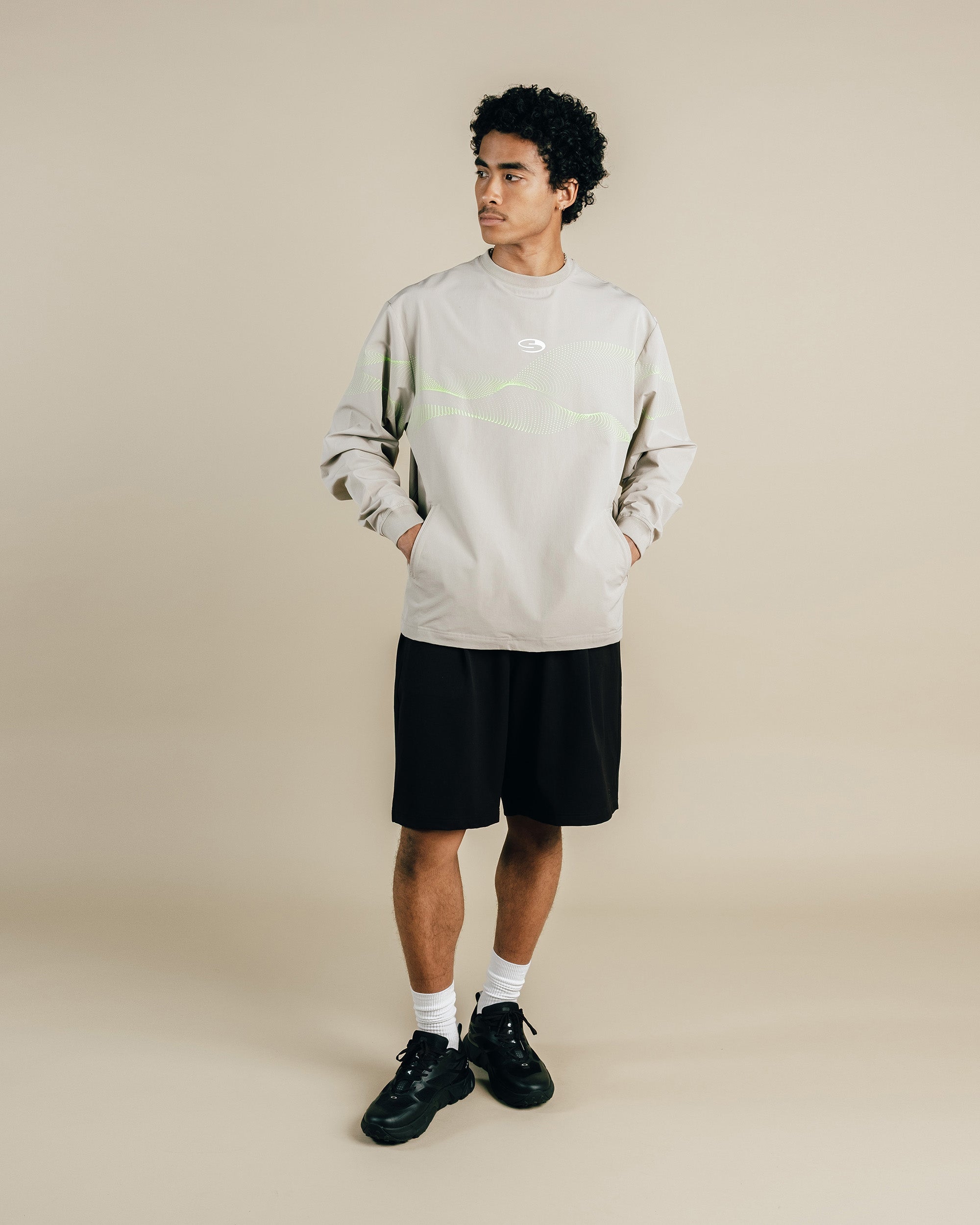 Person wearing a light gray sweatshirt and black shorts on a beige background