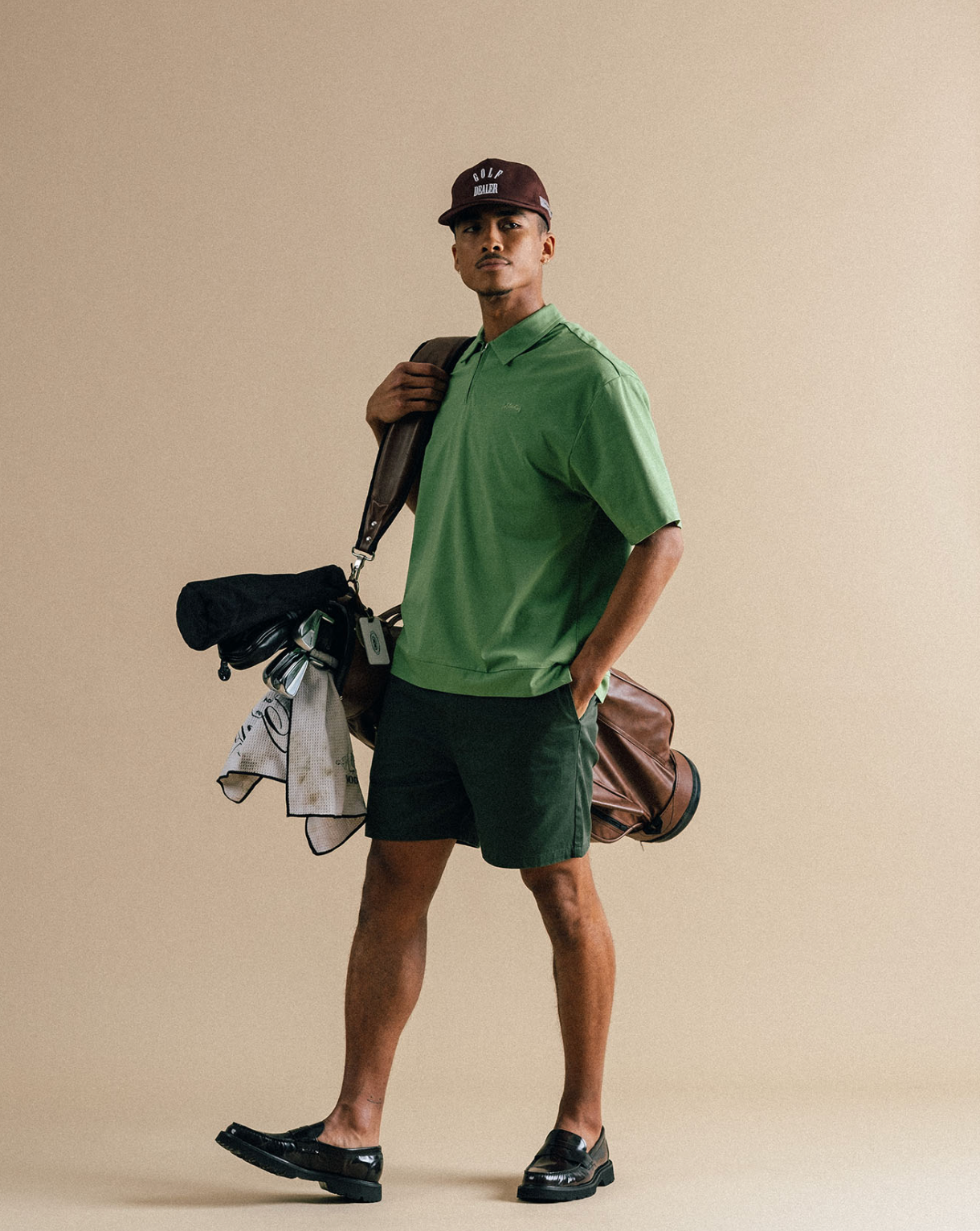 Man holding golf clubs wearing shorts and a polo